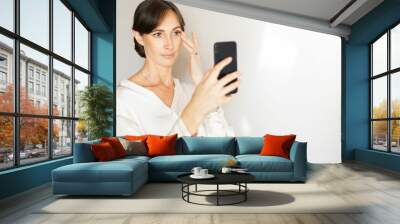 Middle-aged woman taking a selfie with smartphone. Wall mural