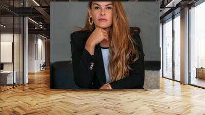 Portrait of a young woman with long hair wearing a black blazer and white top Wall mural