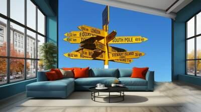 Post with yellow street signs showing various directions. Bluff,  New Zealand. Wall mural