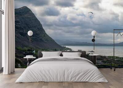 Scenic view of a coastal landscape with a mountain, cloudy sky, and a paraglider over the ocean Wall mural