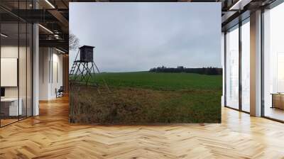 Scenic view of a wooden viewpoint near a pathway in a green open field on a sunny day Wall mural