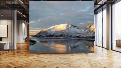 Scenic view of snow-covered mountains reflected in calm water during sunset in Norway. Wall mural