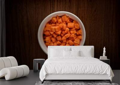 Small bowl of raw diced carrots on a wooden table Wall mural