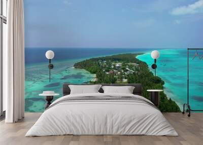 Small green island in the middle of the transparent blue seascape on a sunny day Wall mural