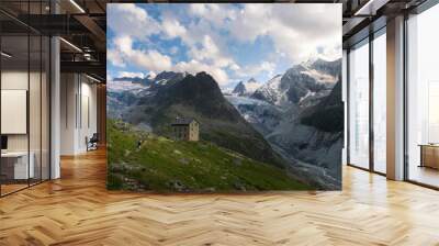 Summer landscape view of a hiker walking to a mountain hut as the sun is setting Wall mural