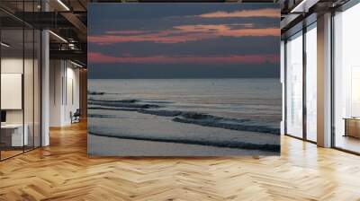 Tranquil beach scene at dusk with gentle waves and a colorful sunset sky. Wall mural