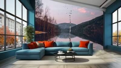 Vertical shot of falling water drop splash on a lake in mountains during sunset Wall mural