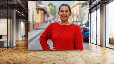 Woman smiling while wearing a red dress in street, exuding happiness and confidence Wall mural