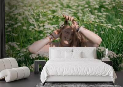 Young woman posing in a field of white wildflowers on a sunny day Wall mural