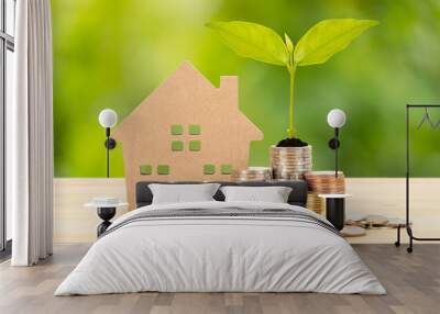 Coin stack and model house on wooden desk on green tree background, mortgage concept Wall mural