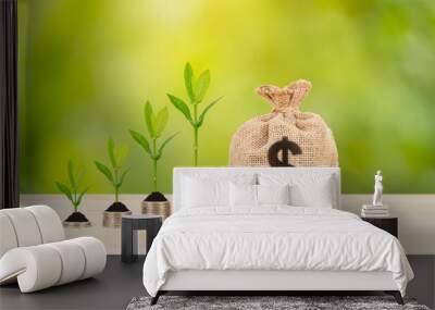 Money sack and leaves with growing coin stack on green tree background, saving concept Wall mural