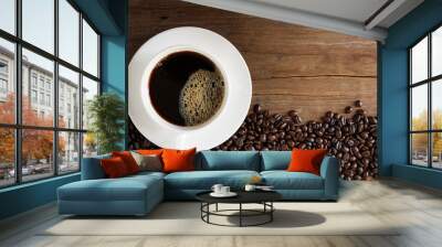 Fresh coffee with fragrant aroma in a white cup and coffee beans on an old wooden table. Top view - image Wall mural