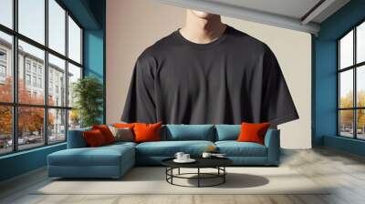 A young man stands confidently in a simple black t-shirt, showcasing a casual and modern style. Wall mural