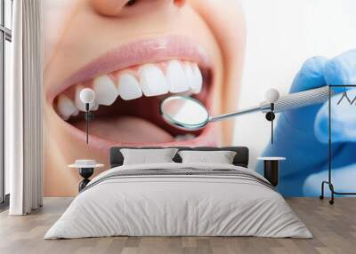 Close-up of a smiling woman at a dental check-up, showcasing healthy teeth and dental tools, white isolated background. Wall mural