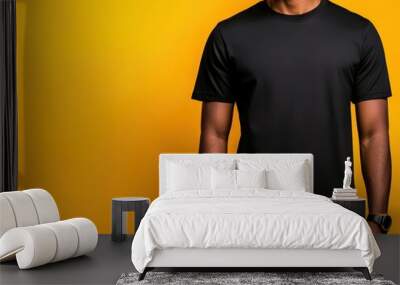 Young man wearing a black t-shirt against a vibrant yellow background showcasing a casual and modern style. Wall mural