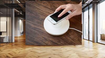 a hand putting mobile phone on a wireless charger, modern equipm Wall mural