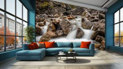 A cascading mountain stream bends and weaves around rocks and boulders, long exposure to create motion blur to the water, nobody in the image Wall mural