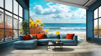 A picnic basket with flowers on the beach with two glasses of juice and a plate of food. Wall mural