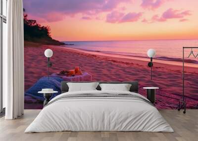 A romantic beach picnic at sunset with a pink and orange sky, a patterned rug, and two glasses of juice. Wall mural