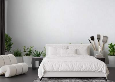 A row of potted plants with gardening tools against a white wall. Wall mural