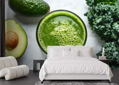 Closeup of a green smoothie with avocado and kale in the background. Wall mural