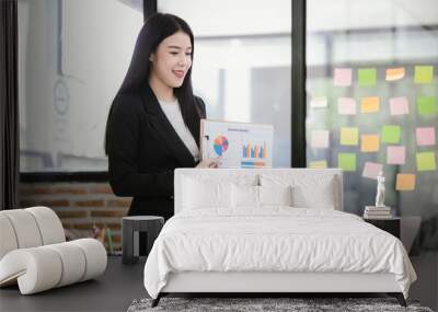 Beautiful Asian businesswoman working on laptop in office Wall mural