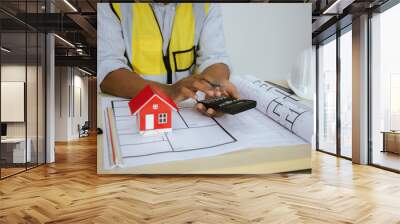 Male architect working at table with toy house model and A3 paper blueprints. Real estate construction law, zoning, permits and resolving property disputes. Wall mural