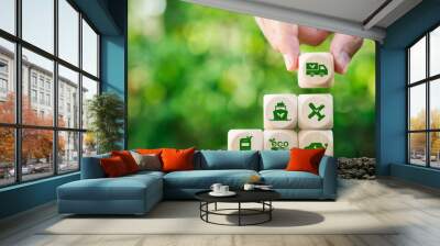 Green logistics concept. Hand holding wooden blocks with Eco friendly Air, sea, and land transport icon. Use technology for invent the clean energy process to Net zero carbon emission. Wall mural