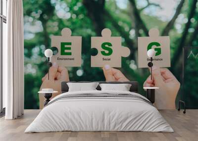 Hand holding Jigsaw with ESG icon concept.ESG icon for environmental, social, and governance in sustainable and ethical business on a green background.Teamwork,renewable,responsibility concept Wall mural