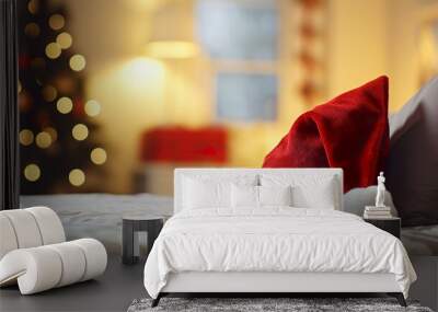 Santa Claus cap on pillow and bed, Christmas home at night. Long holiday Christmas for travel. Wall mural