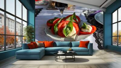 Tasty mozzarella cheese with basil and tomatoes on white plate Wall mural