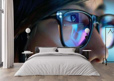 Close-up portrait showing the face of a young woman wearing glasses with a reflection of a computer screen. Wall mural