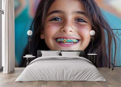 A cheerful young Arabian girl, around 10 years old, smiles proudly, displaying her colorful braces. The close-up captures her excitement and confidence as she poses against a bright backdrop, Wall mural