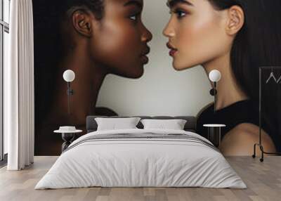 A powerful image of two women of contrasting skin tones, standing face-to-face in perfect symmetry. Their natural beauty is highlighted by the soft light, showcasing the elegance of diversity against Wall mural