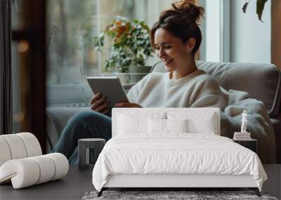 Latin woman relaxing at home she is sitting on the armchair and connecting with her digital tablet contemporary design interior Wall mural