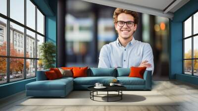 young student stands with folded arms in front of a building Wall mural