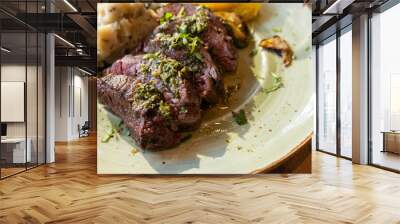 A plate of meat with a side of mashed potatoes and vegetables. The meat is cooked and seasoned perfectly, and the vegetables are roasted. Wall mural