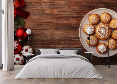 A festive plate of decorated cookies surrounded by Christmas ornaments, set on a rustic wooden surface. Wall mural