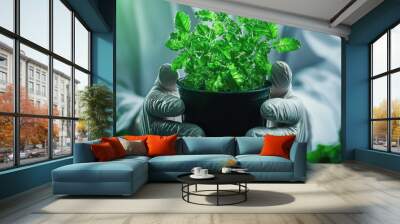 A person in gloves holds a pot of vibrant green plants, symbolizing growth and care in a nurturing environment. Wall mural