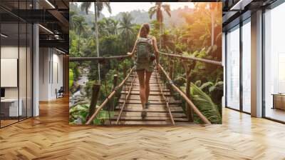 A woman is walking across a wooden bridge in a jungle Wall mural