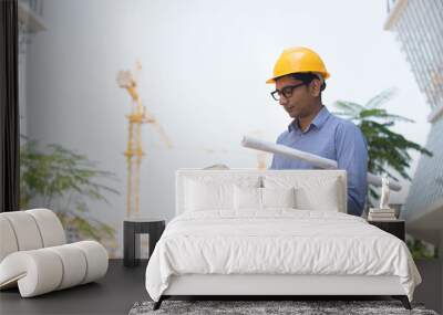 indian male architect holding plans with construction background Wall mural