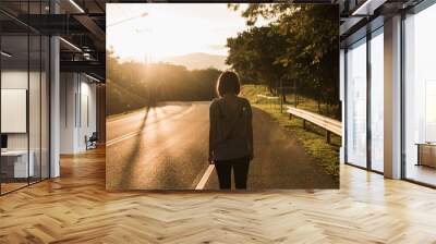 Asia young woman is walking into the sunset in a park Wall mural