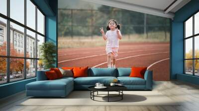 Baby asian girl run jogging at running track, running field at stadium. little girl running at sunset happy baby girl smiling. little girl running at sunset. cute baby girl running at running track. Wall mural