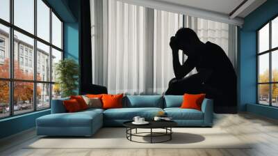 Silhouette depressed man sadly sitting on the bed in the bedroom, depression concept Wall mural