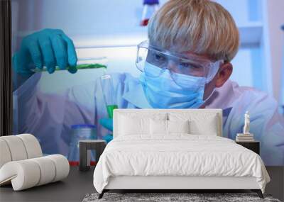 Scientists are doing research in a science lab. A medical chemist in a white coat, gloves and goggles looks at a glass tube. Compare two different liquid samples. and discuss future experiments. Wall mural