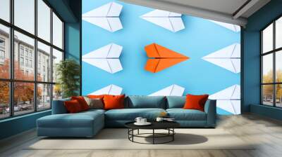 Business concept for new ideas creativity and innovative solution, Group of white paper plane in one direction and one orange paper plane pointing in different way on blue background Wall mural