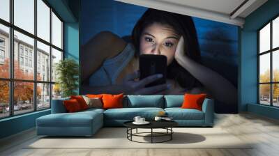 girl in bed using mobile phone late at night at dark bedroom lying happy and relaxed Wall mural