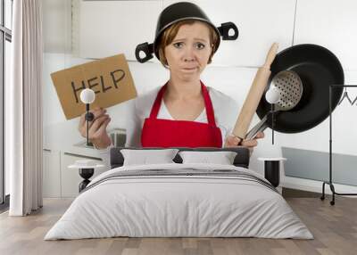 young attractive home cook woman in red apron at  kitchen holding pan and household with pot on her head in stress Wall mural