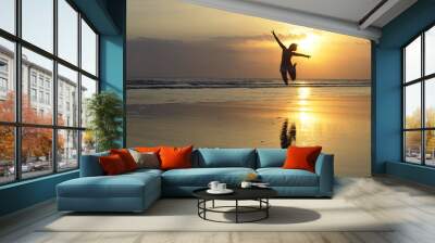 young happy sexy Asian woman in bikini jumping excited on sunset beach having fun Wall mural