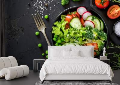 fresh vegetable salad with cucumbers tomatoes radishes greens and a fork on a black background Wall mural